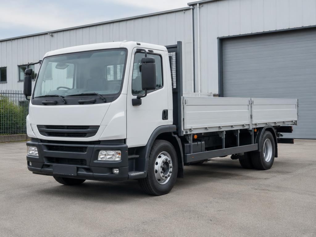 Weißer Lkw mit Pritsche vor dem Werkstattgebäude